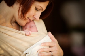 Mother with newborn baby sleeping in baby sling