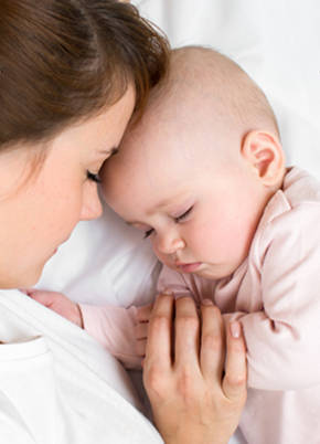 Baby girl settling to sleep next to mother