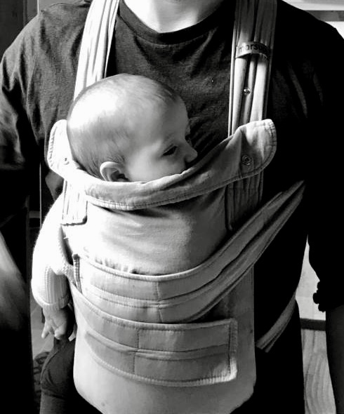 Baby half asleep being carried in a baby carrier