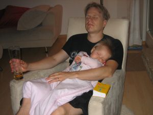 Eleven months old baby sleeping on coach with father