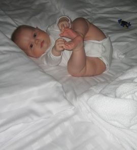 Five and a half months old baby playing on hotel bed