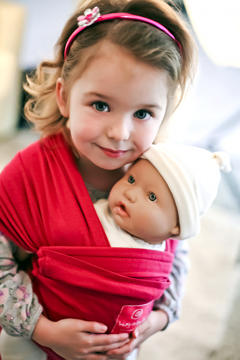 Toddler girl with doll baby carrier