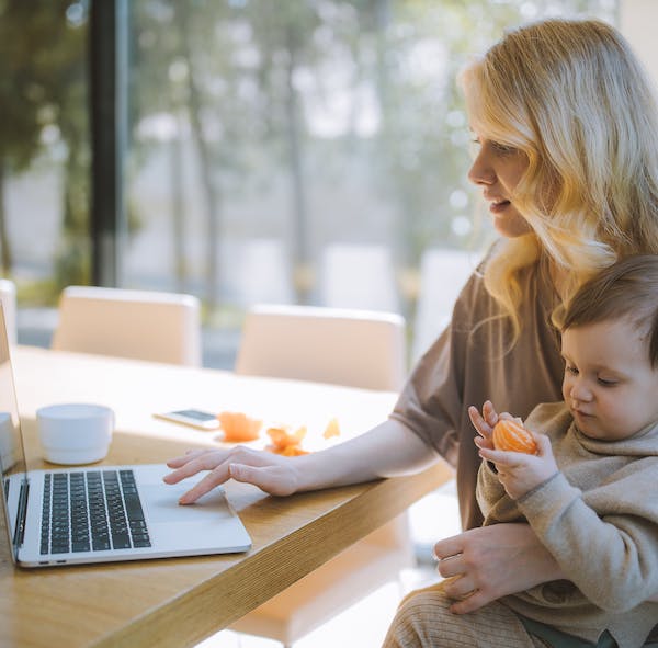Mom and ababy at laptop eating mandarine