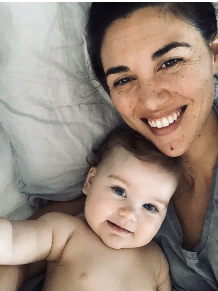 Mom and young baby looking into the camera and smiling