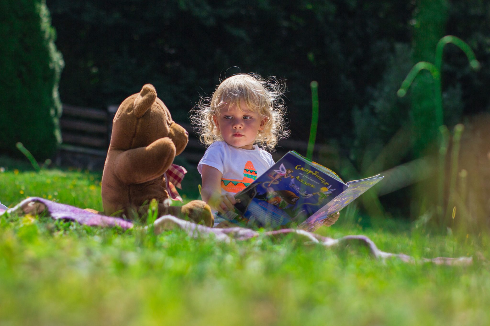 Toddler reading to teddy bear plush toy