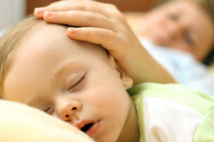 Cosleeping mom with hand on baby s head